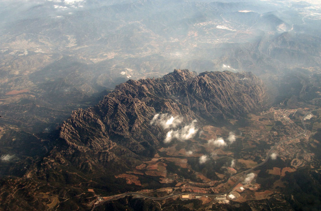 Macizo de Montserrat visto desde el aire, agujas de conglomerado y nubes bajas, sin el monasterio en primer plano.